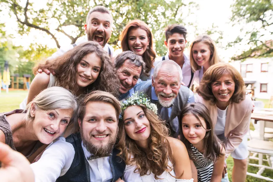 Hochzeitsgesellschaft mit Braut und Bräutigam bei einem Gruppenselfie im Garten
